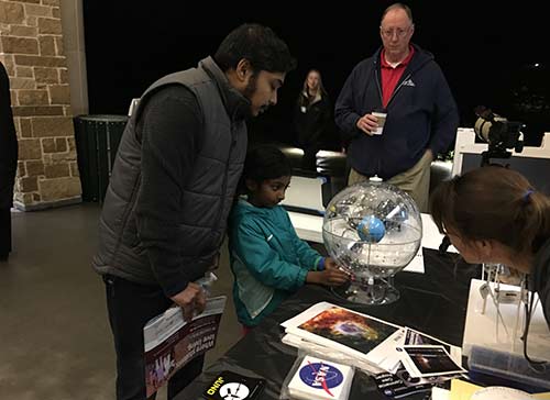 A father and daughter look at Earth/sky model