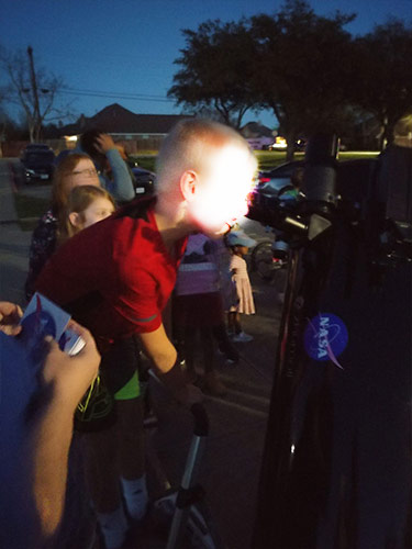 child looking through telescope