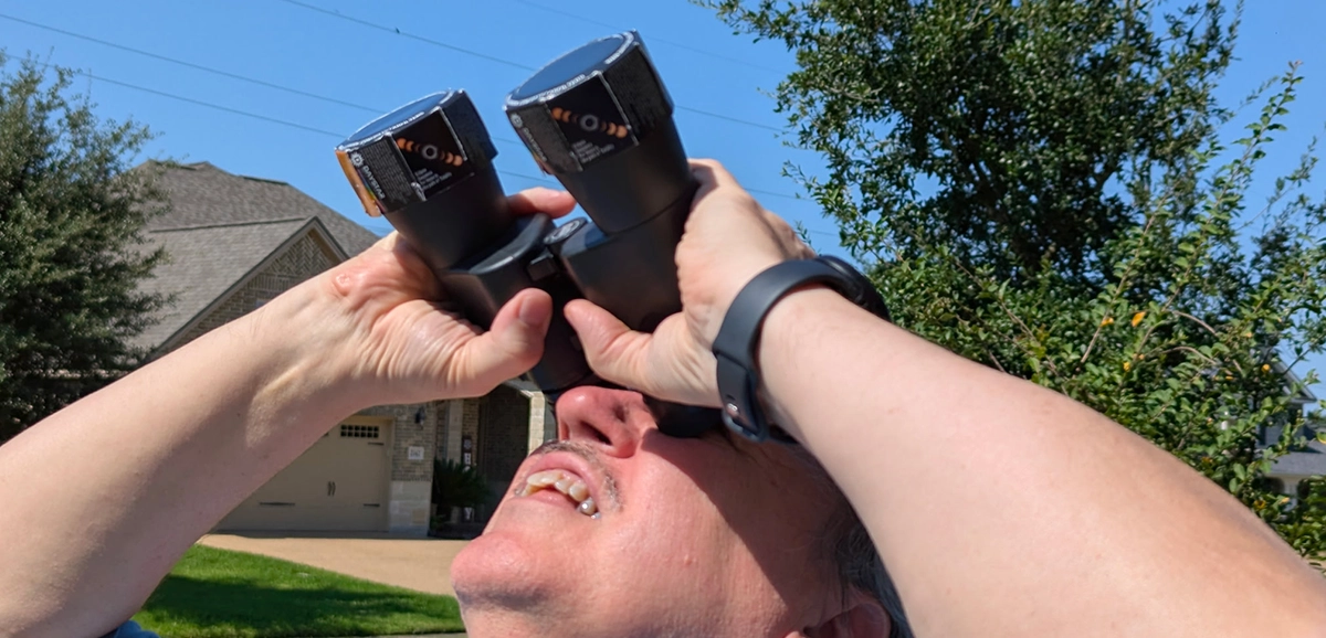 Tom Campbell looking at sun through binoculars protected by solar protector